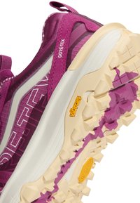 Лилав и бежов туристически обувки Gore-Tex с дебела подметка Vibram, показваща грапава шарка за по-добро сцепление на открито.
