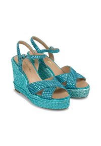 Sandali con tacco wedge turchesi, con cinturini incrociati e decorati con strass. Suola intermedia simile a juta intrecciata e una fodera interna liscia.