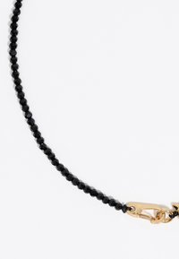 Mustmust beaded ahel, millel on fassaadidega helmed, ja kuldse tooni haak ja aksessuaarid. Kujundus on stiilne ja sirge.