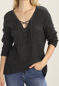 Grauer Strickpullover mit V-Ausschnitt und Schnürdetails, langen Ärmeln und lockerer Passform. Strukturiertes Gewebe und Rippmuster.