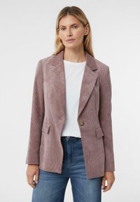 Corduroy blazer in stoffige rozenkleur, met notch-lapels, een enkele knoopsluiting en twee voorzakken. Gecombineerd met een witte top en blauwe jeans.