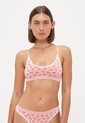 Lichtroze geribbelde bralette met rood kersenmotief, kantdetail en verstelbare bandjes, gecombineerd met bijpassende bikinionderkant met kantaccent.