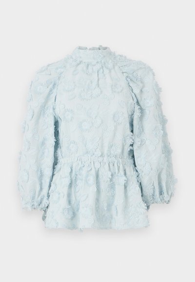Svetlo modra bluzica z rožnatim vezenjem, z zbranim pasom, visokim ovratnikom in napihnjenimi rokavi, izdelana iz strukturiranega materiala.