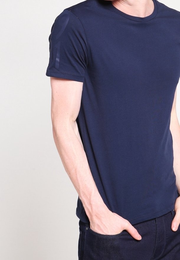 Námořnická modrá bavlněná tričko s krátkým rukávem, kulatým výstřihem a jemným texturovaným detailem na rameni. Hladká tkanina s přiléhavým střihem.