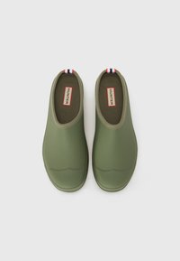 Olívazöld, slip-on cipők sima, matt felülettel, lekerekített szélekkel és csíkozott füllel a hátsó részén. A belső része párnázott és texturált.