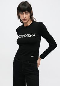 Schwarzer Strickpullover mit dem Schriftzug "ASPEN" in weißen Buchstaben, gerippten Bündchen und einer taillierten Passform mit einem kleinen Logoakzent am Saum.