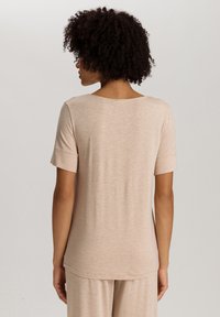 Korte mouwen beige top van zachte stof, met een ronde hals en een iets verlengde achterkant voor een ontspannen pasvorm.