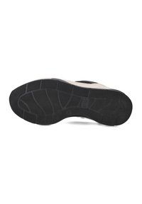 Black rubber shoe sole with a textured pattern, featuring a cream-colored edge and segmented grip lines for traction.