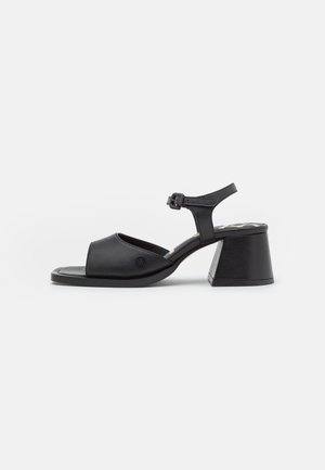 Black leather sandal with an open toe, ankle strap, and a block heel. Smooth texture with a slightly glossy finish.