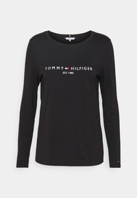 Musta pitkähihainen t-paita, joka on valmistettu puuvillasta ja jossa on valkoiset kirjailutekstit "TOMMY HILFIGER EST. 1985" rinnassa sekä pieniä logokoristeita.