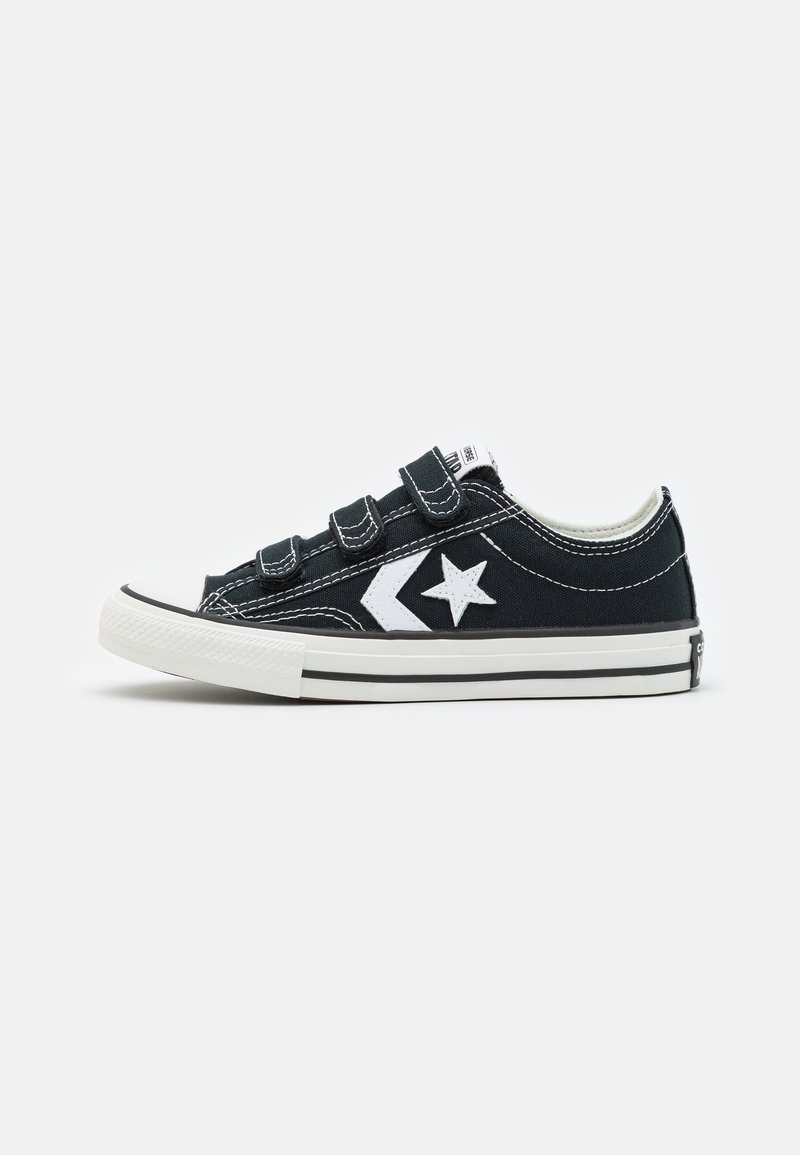 Sorte kanvas sneakers med hvite detaljer, med borrelås-lukking, rund tå og kontrasterende hvit gummisåle.