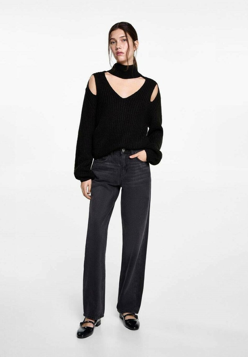 Čierny pletený sveter s vysokým golierom, s vystrihmi na pleciach a V-výstrihom. V páre s čiernymi džínsami s vysokým pásom a rovnými nohavicami. Čierne topánky.