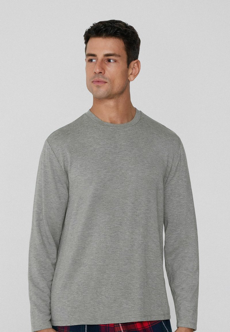 Šedé tričko s dlouhým rukávem z měkké látky. Má kulatý výstřih a volný střih. Jednoduchý design bez vzorů či zdobení.