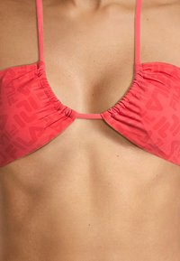 Top bikini corallo realizzato in tessuto testurizzato con un design arricciato, dotato di spalline regolabili e un discreto motivo a logo.