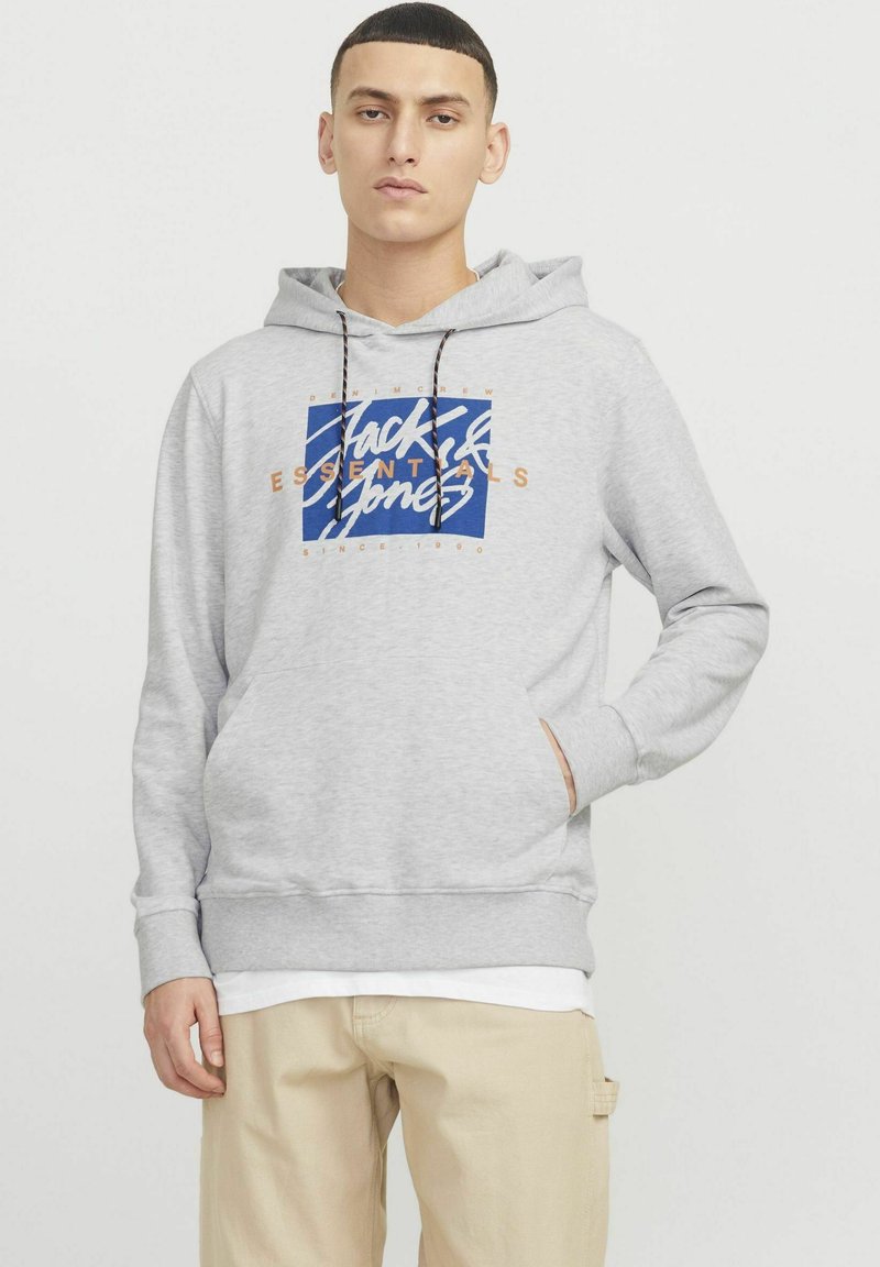 Felpa grigia chiara con cappuccio e lacci, tasca frontale e una grafica blu con la scritta "Jack & Jones Essentials" in bianco e arancione.