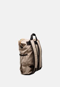 Zaino in nylon beige con spallacci neri, apertura a coulisse e dettaglio a strisce a contrasto. Presenta una tasca laterale e una superficie testurizzata.