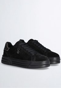 Black suede sneakers with textured accents, rounded toe, and black rubber soles. Features lace-up design and logo detail on the side.