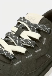 Σκούρο γκρι σουέντ αθλητικό παπούτσι με λευκά κορδόνια και ραμμένες λεπτομέρειες. Διαθέτει υφασμένη πλαϊνή επιφάνεια και λογότυπο στη γλώσσα. Ποιοτικός, αθλητικός σχεδιασμός.