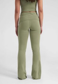 Olijfgroene fitted top en uitlopende legging gemaakt van rekbare, gladde stof; heeft een heuplange ontwerp met een naadloze tailleband.