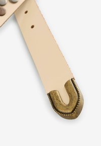 Cintura in pelle con hardware a forma di U in ottone, caratterizzata da una superficie beige liscia e rivetti lungo la lunghezza per un tocco di dettaglio in più.