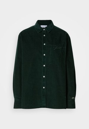 Camicia a maniche lunghe in corduroy verde scuro con chiusura a bottoni, colletto, taschino sul petto, logo ricamato sottile e polsini con bottoni.