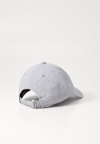 Gorra de béisbol de algodón gris con visera curva, correa de tela en la parte posterior y orificios de ventilación cosidos. Textura suave y diseño sencillo.