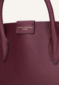Borsa in pelle texturizzata di un profondo bordeaux con due manici e una piccola patta che presenta il logo dorato "Gianni Chiarini Firenze".