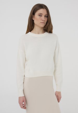 Maglione bianco a maglia con scollo rotondo, maniche lunghe e polsini a costine. Tessuto liscio con una vestibilità leggermente accorciata.