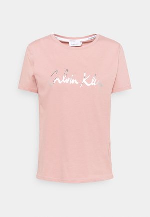 Różowa bawełniana koszulka z okrągłym dekoltem i krótkimi rękawami. Z przodu znajduje się srebrne, odblaskowe logo "Calvin Klein".