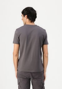 Graues Baumwoll-T-Shirt mit kurzen Ärmeln, rundem Ausschnitt und glatter Textur. Sichtbare Nähte entlang der Schultern und des Saums.