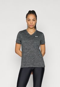 T-shirt grigio a maniche corte con scollo a V, tessuto strutturato e piccolo logo bianco sul petto, abbinata a leggings sportivi neri.