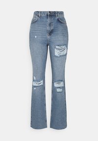 Pantalones vaqueros de mezclilla azul con cintura alta, piernas acampanadas, detalles desgastados y parches rasgados en la parte delantera. Tejido texturizado con costuras visibles.