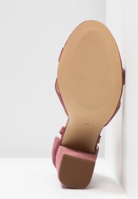 Talons en suède rose avec une semelle texturée beige, présentant un large talon bloc et un bout lisse légèrement arrondi. Taille 37 imprimée sur la semelle.