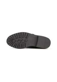Suela de zapato de goma negra con un patrón de tracción profundo; presenta formas de cruz elevadas y una superficie texturizada; construcción sólida con un mínimo de marca.