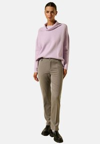 Pull léger en maille violette avec un col drapé, associé à un pantalon gris ajusté et des chaussures à lacets noires. Tenue simple et structurée.