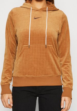 Haut à capuche en velours côtelé marron avec une surface texturée, cordons blancs, poche avant et un petit logo sombre sur la poitrine.