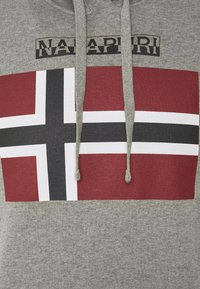 Sudadera gris con un gran diseño de la bandera noruega en rojo y blanco, con acentos negros. Incluye cordones y una etiqueta impresa.