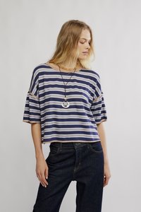 Majica s kratkimi rokavi z rjavimi in svetlo kremnimi črtami, sproščenega kroja z neobdelanim robom. Kombinirana s temnimi džins hlačami.