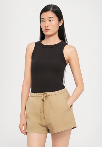 Black ribbed tank top with a round neckline, paired with beige shorts featuring an elastic waistband and side pockets.