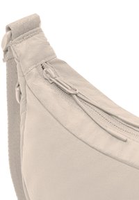 Borsa a tracolla in tessuto beige chiaro con tasca con zip, morbida al tatto, design curvato e tracolla regolabile per il massimo comfort.