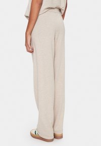 Beige weite Beinhosen aus weichem, strukturiertem Stoff, mit elastischem Bund und lässiger Passform, kombiniert mit bequemen Schuhen.