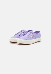 Sneakers in tela viola con suole in gomma bianca. Le caratteristiche includono punta rotonda, design con lacci e un piccolo logo sul lato.