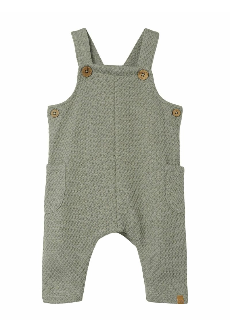Pantalones de tirantes de algodón tejido en verde claro, con tela texturizada, botones de madera, dos bolsillos laterales y un pequeño parche con el logo en el dobladillo.