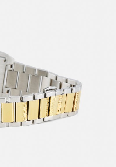 Relógio em aço inoxidável com tons prateado e dourado, apresentando um design de bracelete robusto. Possui detalhes gravados e um acabamento polido.