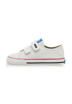 Zapatillas de lona blancas con dos tiras de velcro, rayas rojas y negras en la suela y un acento azul en el talón. Diseño de punta redonda y plana.