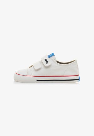 Zapatillas de lona blancas con dos tiras de velcro, rayas rojas y negras en la suela y un acento azul en el talón. Diseño de punta redonda y plana.