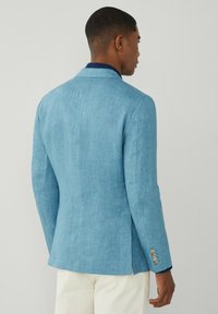 Blazer in lino blu chiaro con un design sartoriale, un'apertura posteriore singola e dettaglio a tre bottoni sui polsini. Texture liscia, vestibilità slim.