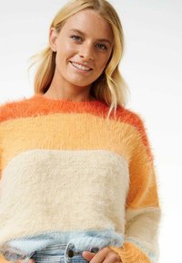 Suéter esponjoso de rayas múltiples en naranja, amarillo y crema, con un corte holgado y una textura suave, con un dobladillo azul claro en la parte inferior.