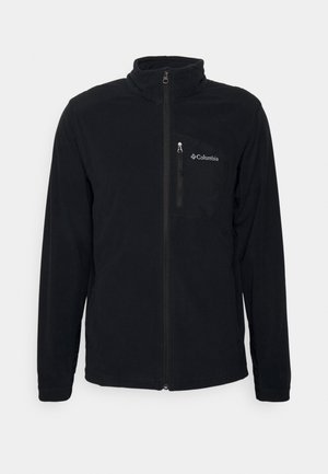 Veste polaire Columbia noire avec fermeture éclair intégrale à l'avant, poche poitrine zippée et col montant, affichée sur fond blanc.