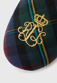 Tumši zaļa un tumši zila rūtainā auduma ar dzeltenām, tirkīza un sarkanām svītrām, izšūti ar zelta greznām burtiem un kroņa simbolu.